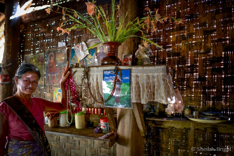 A Burmese woman shows off the shrine in her home.